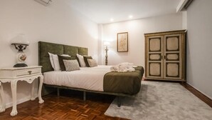 A bedroom with a bed, a nightstand, a lamp, a wardrobe, and a carpet.