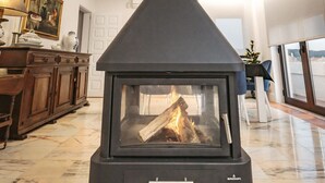 A modern fireplace with a black chimney, marble flooring, and a wooden cabinet to the left.