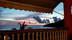 A balcony with a view of the ocean and a sunset. - Feet in the water 2 (Les Anses-d'Arlets)