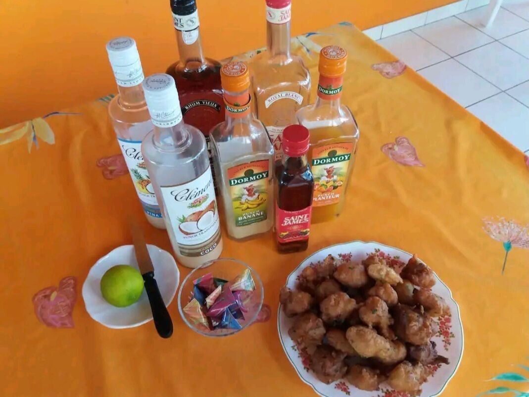Een tafel met verschillende flessen drank, een bord gebakken snacks, een limoen en een mes.