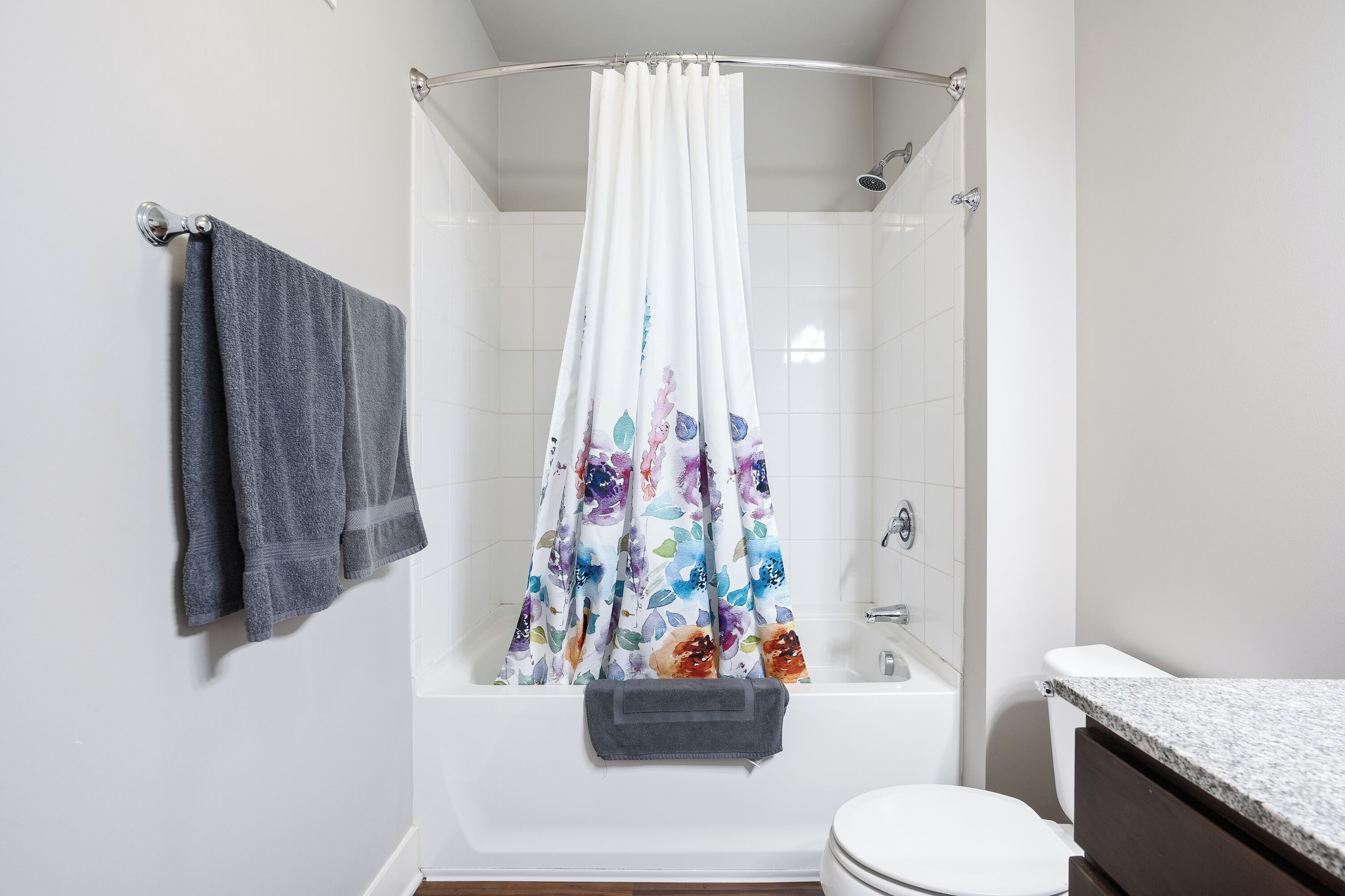 A bathroom with a shower curtain, a towel rack, and a toilet.