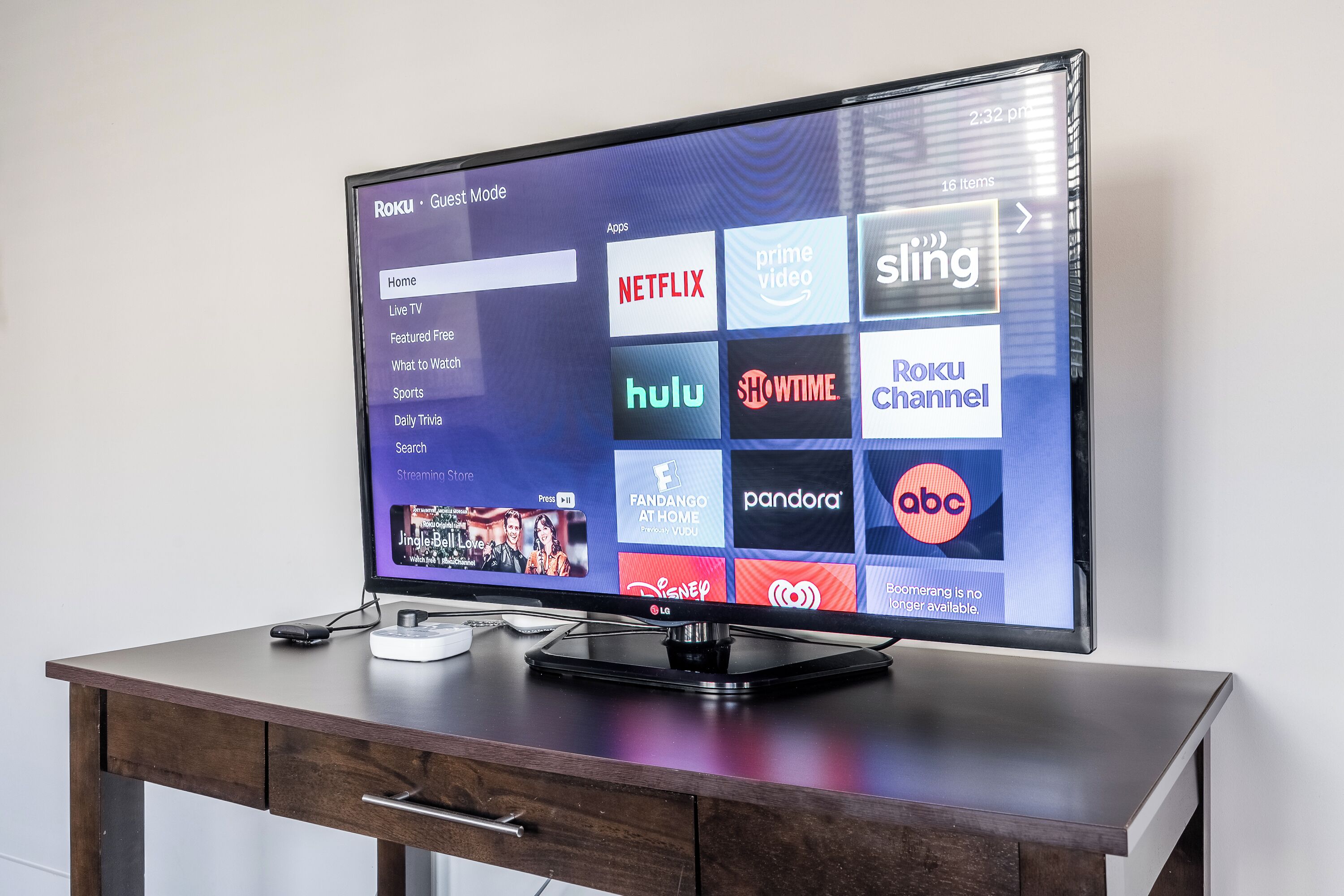 Un televisore a schermo piatto su una scrivania in legno mostra un'interfaccia Roku con diverse app di streaming.