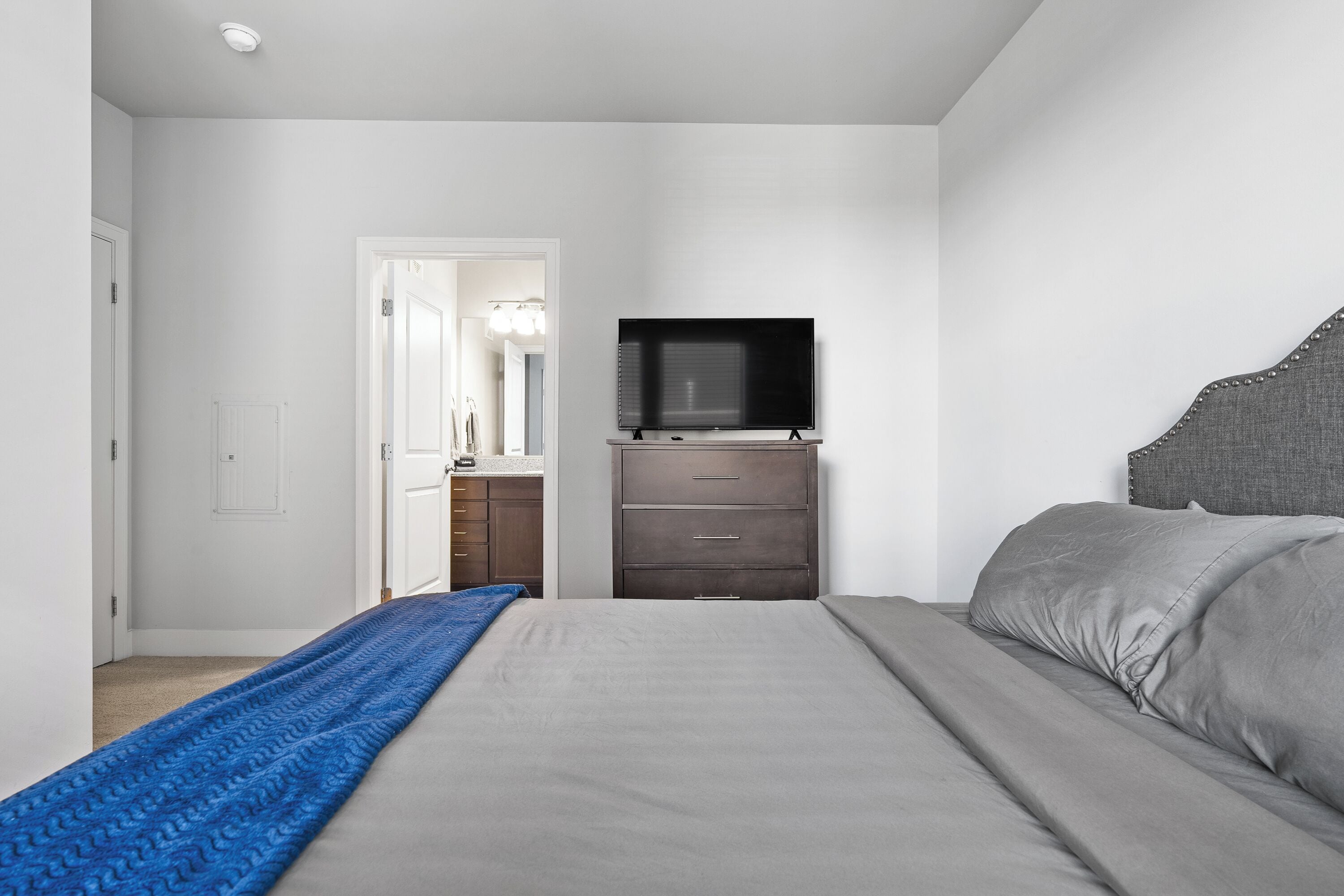 A bedroom with a bed, a dresser, and a TV.