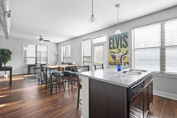 A modern kitchen with a central island, bar stools, and a dining area with a table and chairs.