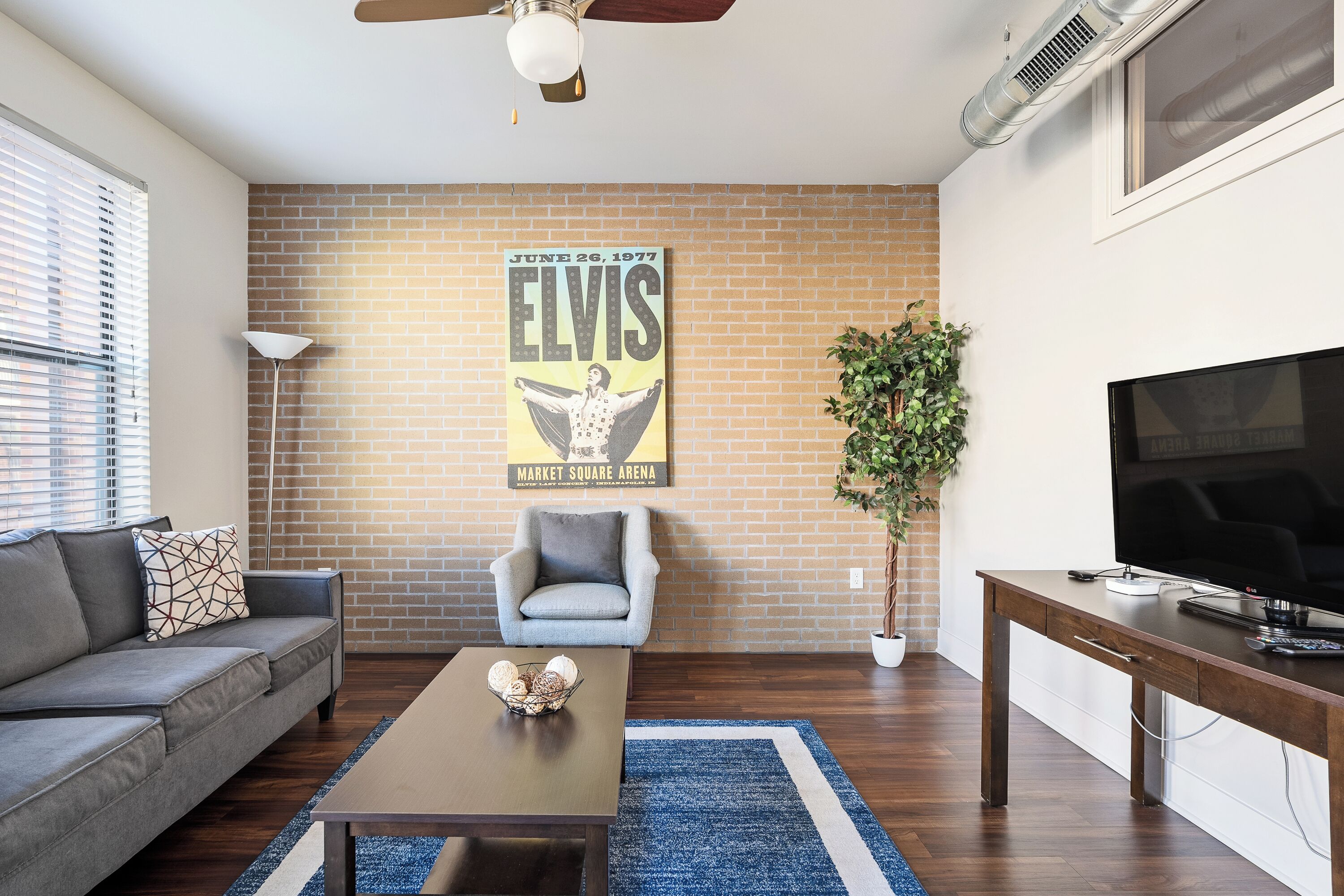 A living room with a sofa, a coffee table, a TV stand, and a poster on the wall.