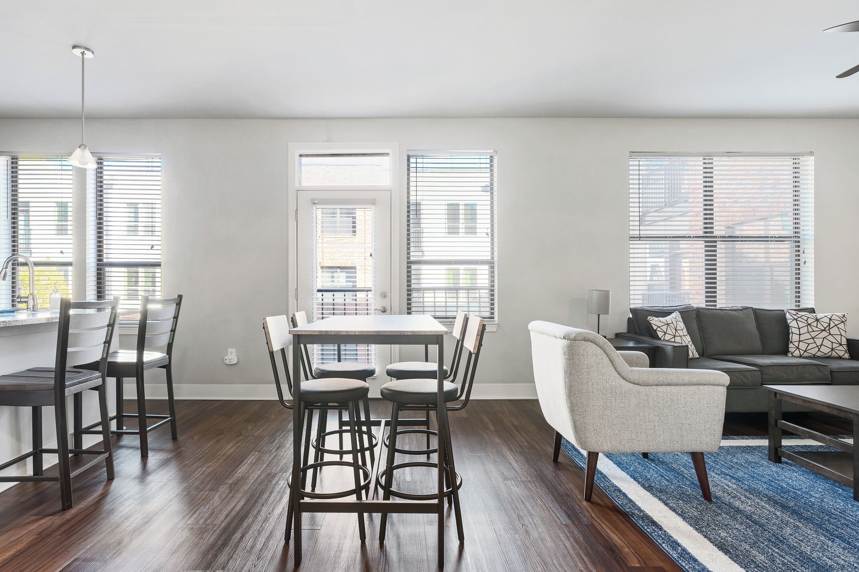 A modern living room with a dining area, featuring a sofa, chairs, and a table.