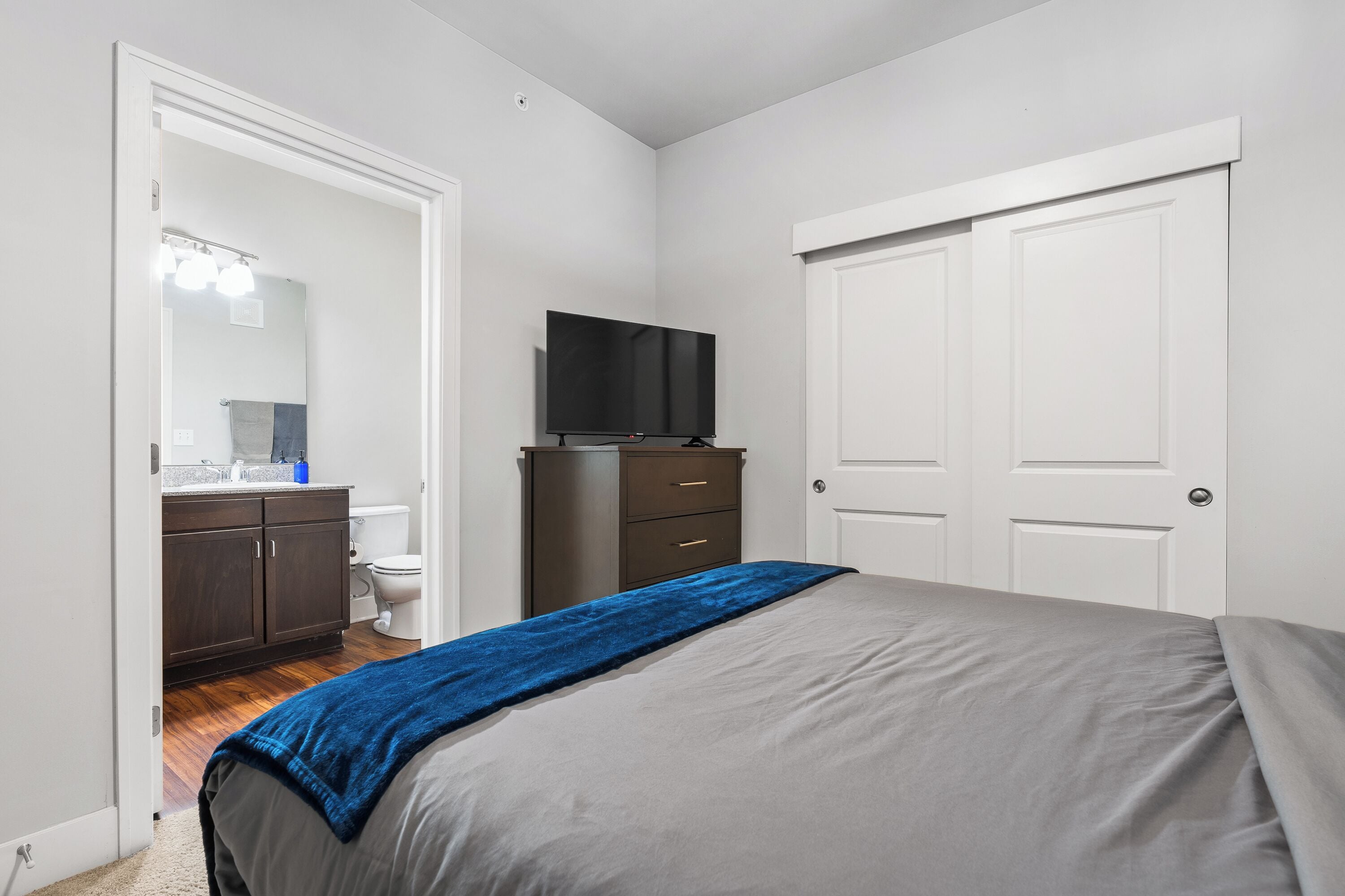 A bedroom with a bed, a television, a wardrobe, and a bathroom visible through an open door.