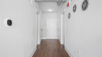 A hallway with wooden flooring, white walls, and a white door at the end.