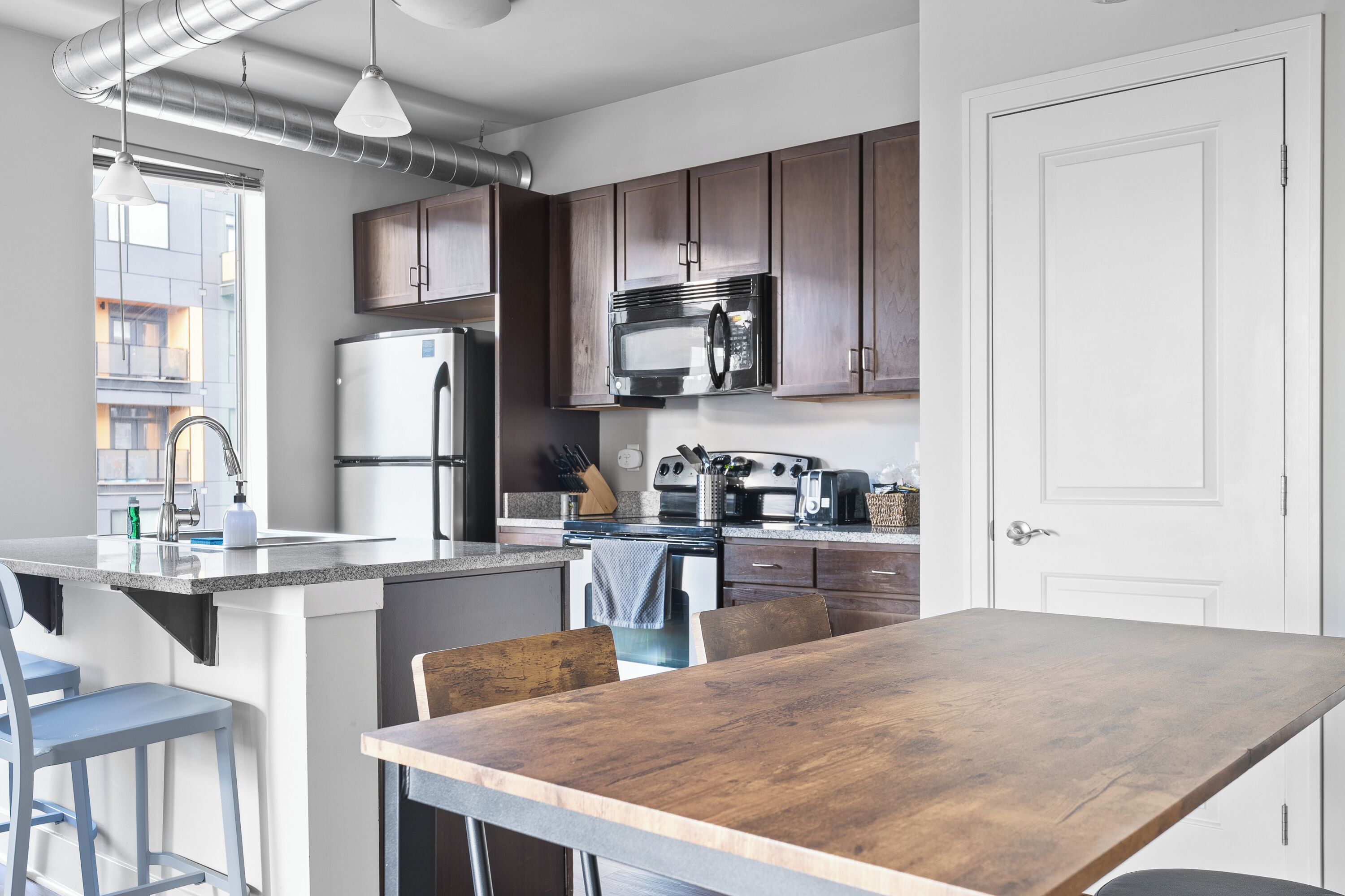 Una cocina moderna con una isla central, electrodomésticos de acero inoxidable y armarios de madera.