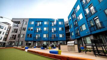 A modern building with multiple floors, outdoor seating area, and a barbecue grill.