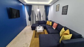 Ein modernes Wohnzimmer mit einer Eckcouch, einem Couchtisch und einem flachbildfernseher an der Wand.