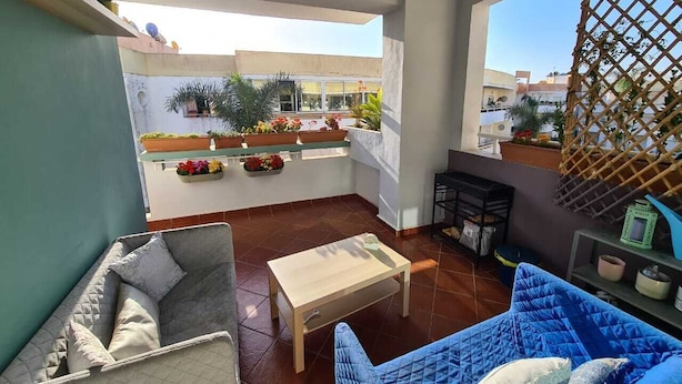 Ein Balkon mit einer Couch, einem Tisch und Topfpflanzen.