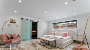 Un dormitorio con cama, mesitas de noche, un banco, un sofá y una ventana con vistas.