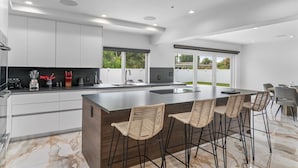Una cocina moderna con una isla grande, taburetes de bar y un comedor con sillas.