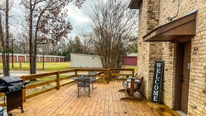 A wooden deck with outdoor seating, a barbecue grill, and a 'Welcome' sign.
