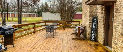 A wooden deck with outdoor seating, a barbecue grill, and a 'Welcome' sign.