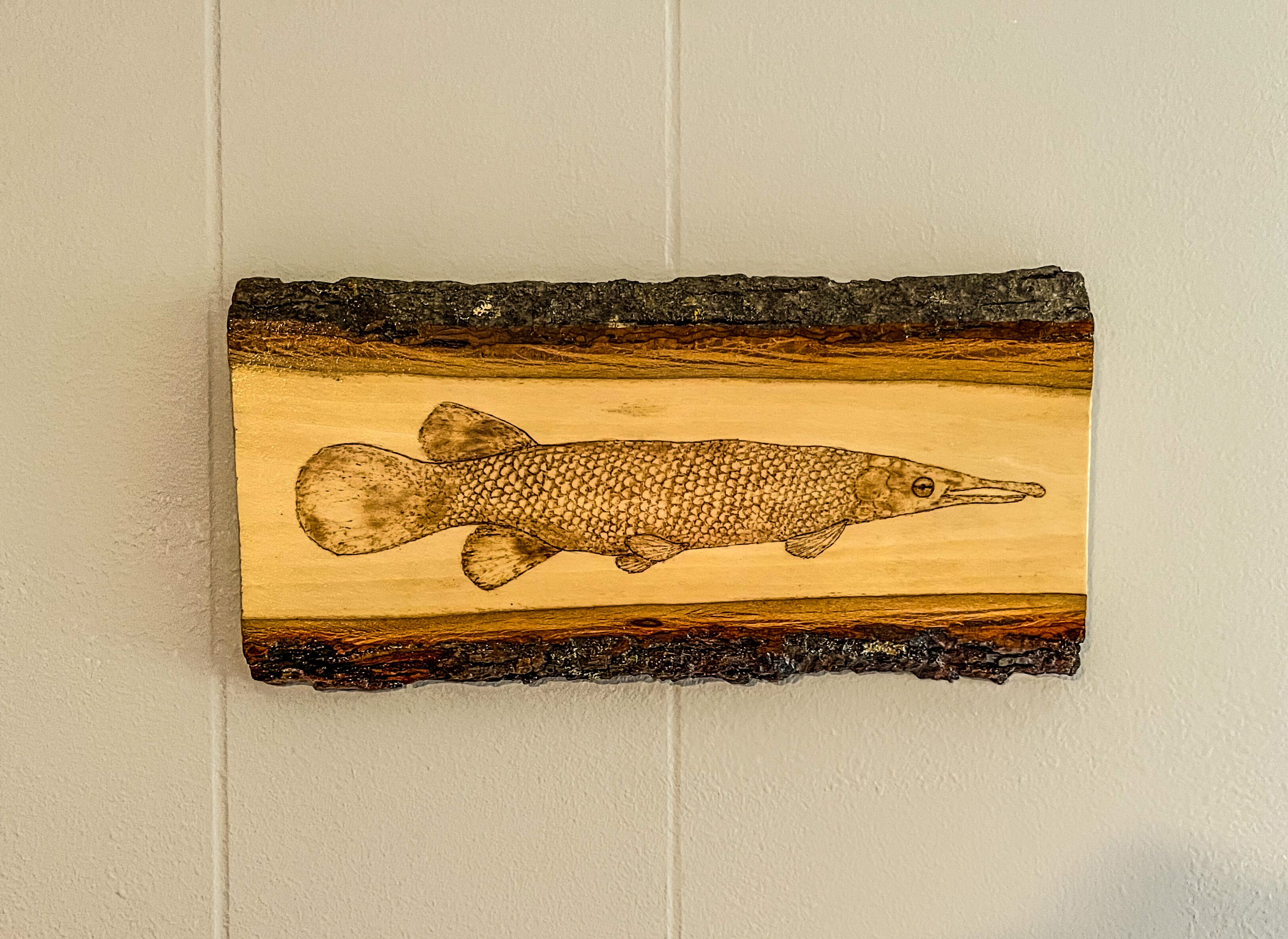 Une sculpture murale en bois représentant un poisson.