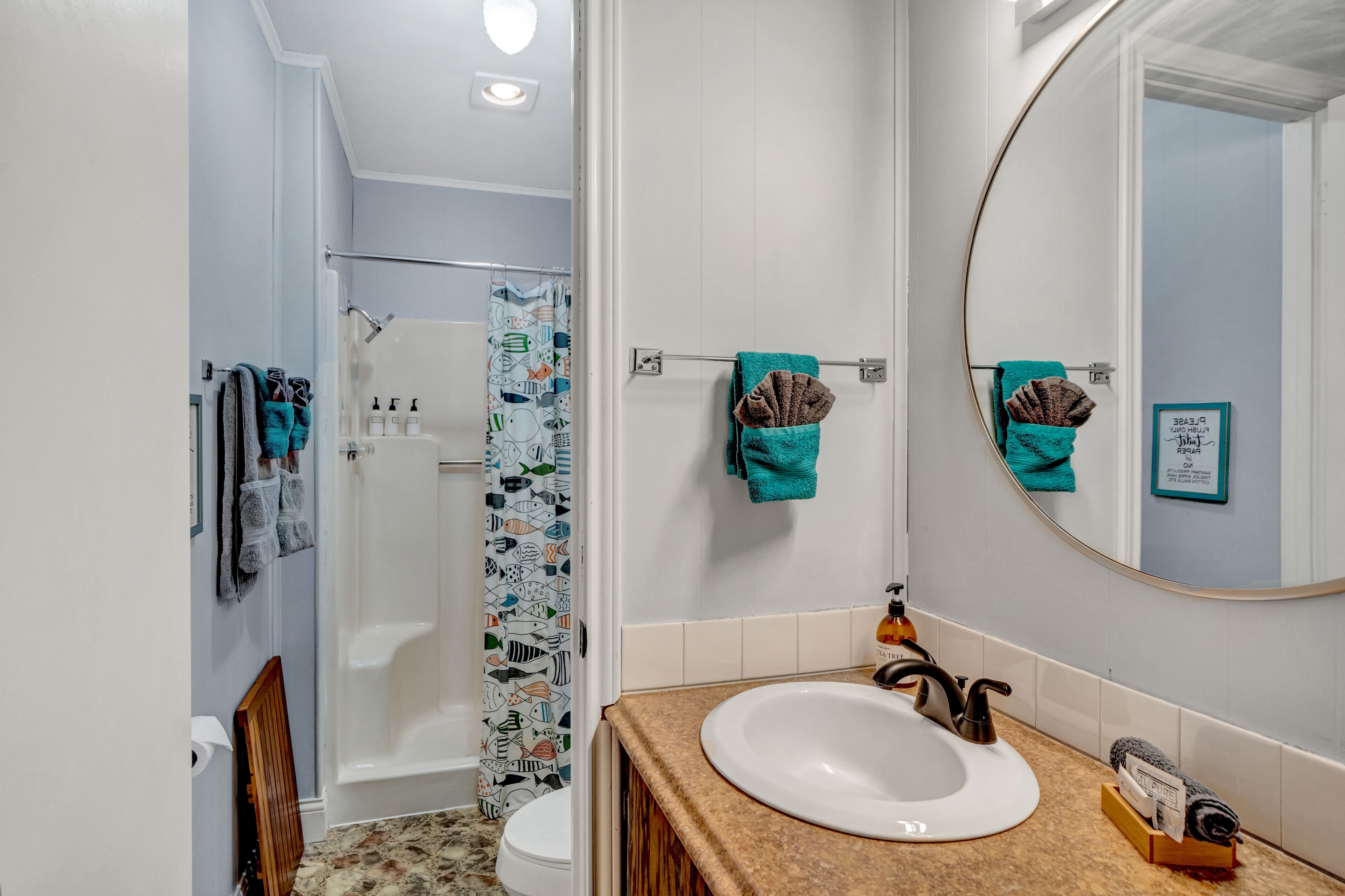 Un baño con ducha, inodoro, lavamanos y espejo.