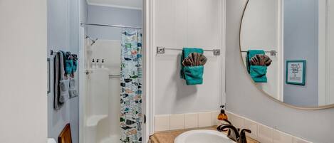 Un baño con ducha, inodoro, lavamanos y espejo.
