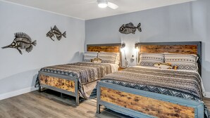 A bedroom with two beds, a ceiling fan, wall-mounted fish decorations, and a wooden headboard. - Reel Inn and Lodge (Quitman)