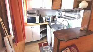 A compact kitchen with white cabinets, a microwave, a toaster, a sink, and a small table. - Apartment T2, MOUNTAIN VIEW, center, ski, cures, close to cable cars and thermal baths (Bagnères-de-Luchon)