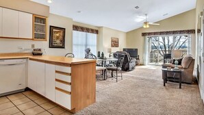 A spacious living area with a kitchen, dining table, and a large window. - Lux 2BR Condo w/Jacuzzi, fast Wifi, Clubhouse, Gym (Branson)