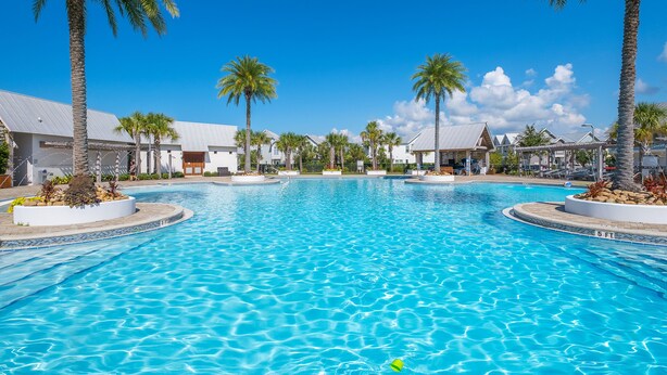 Une grande piscine entourée de palmiers et de bâtiments modernes.