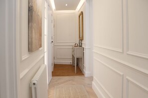 Un couloir avec un radiateur, un miroir et une petite coiffeuse dotée de tiroirs.