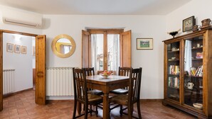 Ein Essbereich mit Holztisch und Stühlen, einem Spiegel an der Wand und einem Schrank mit Glastüren.