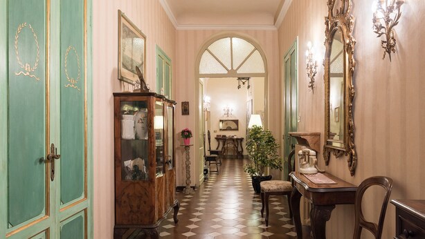 A hallway with a checkered floor, a wooden cabinet with glass doors, a desk with a telephone, and a mirror on the wall. - Perfect Florence Location-Upscale Historic-AC-2 Bathrooms-Lift-Washer (Florence)