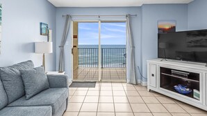 Un soggiorno con divano, televisione e balcone vista mare.