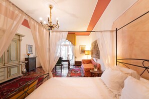 A bedroom with a large bed, a chandelier, a sofa, a table, and a chair. - Perfect Heart of Florence-Super Upscale Location-Roomy-Washer-Elevator (Florence)