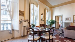 A dining area with a round table, four chairs, a vase with flowers, and a potted plant. - Perfect Heart of Florence-Super Upscale Location-Roomy-Washer-Elevator (Florence)