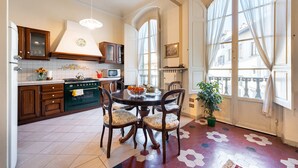 A kitchen with a dining table, chairs, a stove, cabinets, and a window with curtains. - Perfect Heart of Florence-Super Upscale Location-Roomy-Washer-Elevator (Florence)