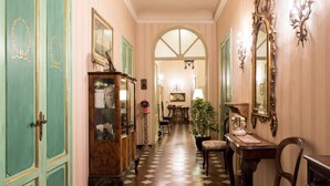 A hallway with a checkered floor, a wooden cabinet with glass doors, a desk with a telephone, and a mirror on the wall. - Perfect Heart of Florence-Super Upscale Location-Roomy-Washer-Elevator (Florence)