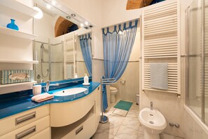 A bathroom with a blue countertop sink, a mirror, a towel rack, a bidet, and a shower curtain. - Perfect Heart of Florence-Super Upscale Location-Roomy-Washer-Elevator (Florence)