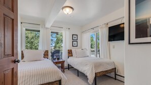 A bedroom with two beds, a wooden door, a ceiling light, and a TV on the wall. - 🏔️Ski-In, Ski-Out Condo~Hot Tub~Interlude 203🏔️ (Snowmass Village)