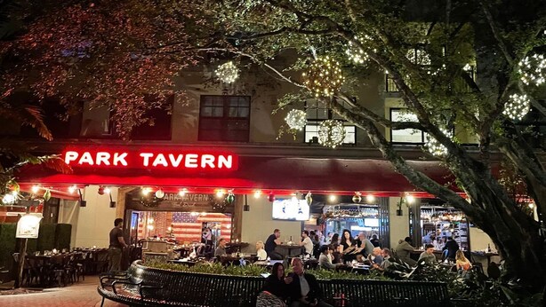 A nighttime view of a restaurant named 'Park Tavern' with outdoor seating and illuminated decorations. - Lux King Bed Suite, Modern Condo Delray Beach. DRClub - 40% Off Fall & Holidays (Delray Beach)