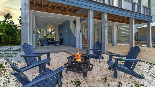 Una casa de playa con un porche cubierto, mobiliario exterior y una chimenea.