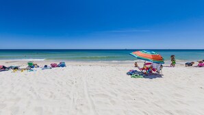 Una playa de arena blanca, cielo azul despejado y mar tranquilo.