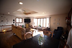 A spacious living area with a high ceiling, a ceiling fan, a dining table with chairs, a sofa, and a television. - 3BR/3BA large house near Red River Gorge (Beattyville)