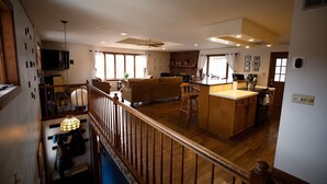 A spacious kitchen with a central island, wooden flooring, and a staircase leading to an upper level.