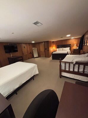 Une chambre d’hôtel avec deux lits, un bureau, une chaise, une télévision et un lambris en bois.