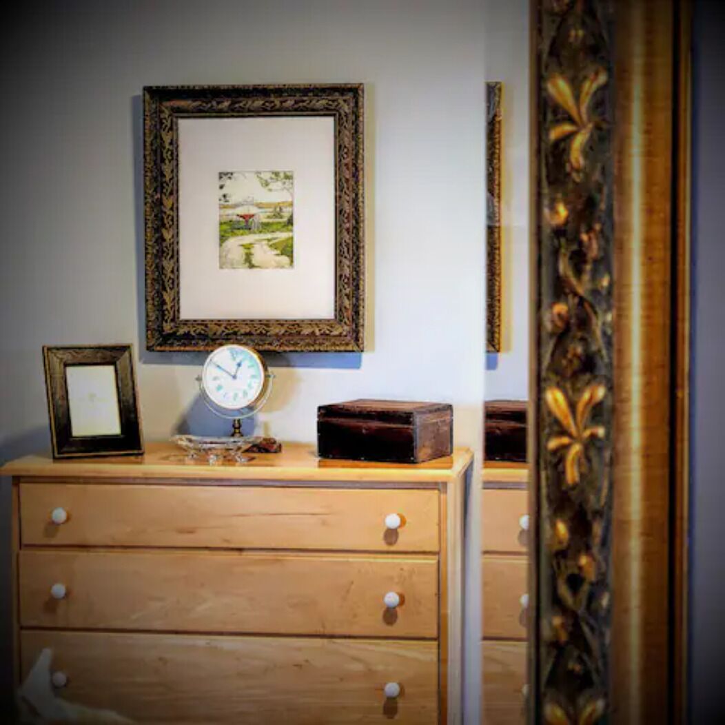 Een houten dressoir met een klok en een lijst met foto.