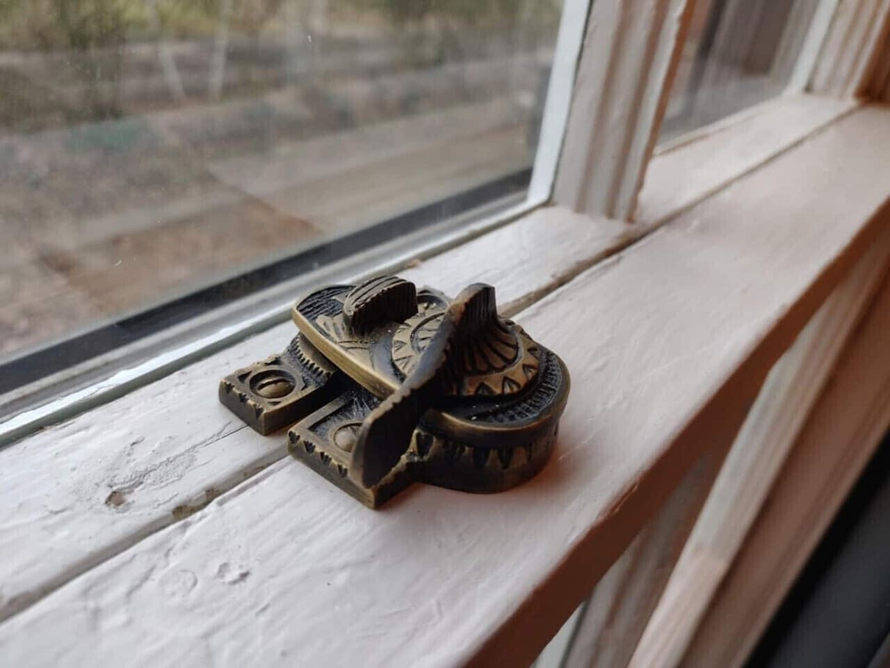 Un objeto decorativo de bronce sobre un alféizar.