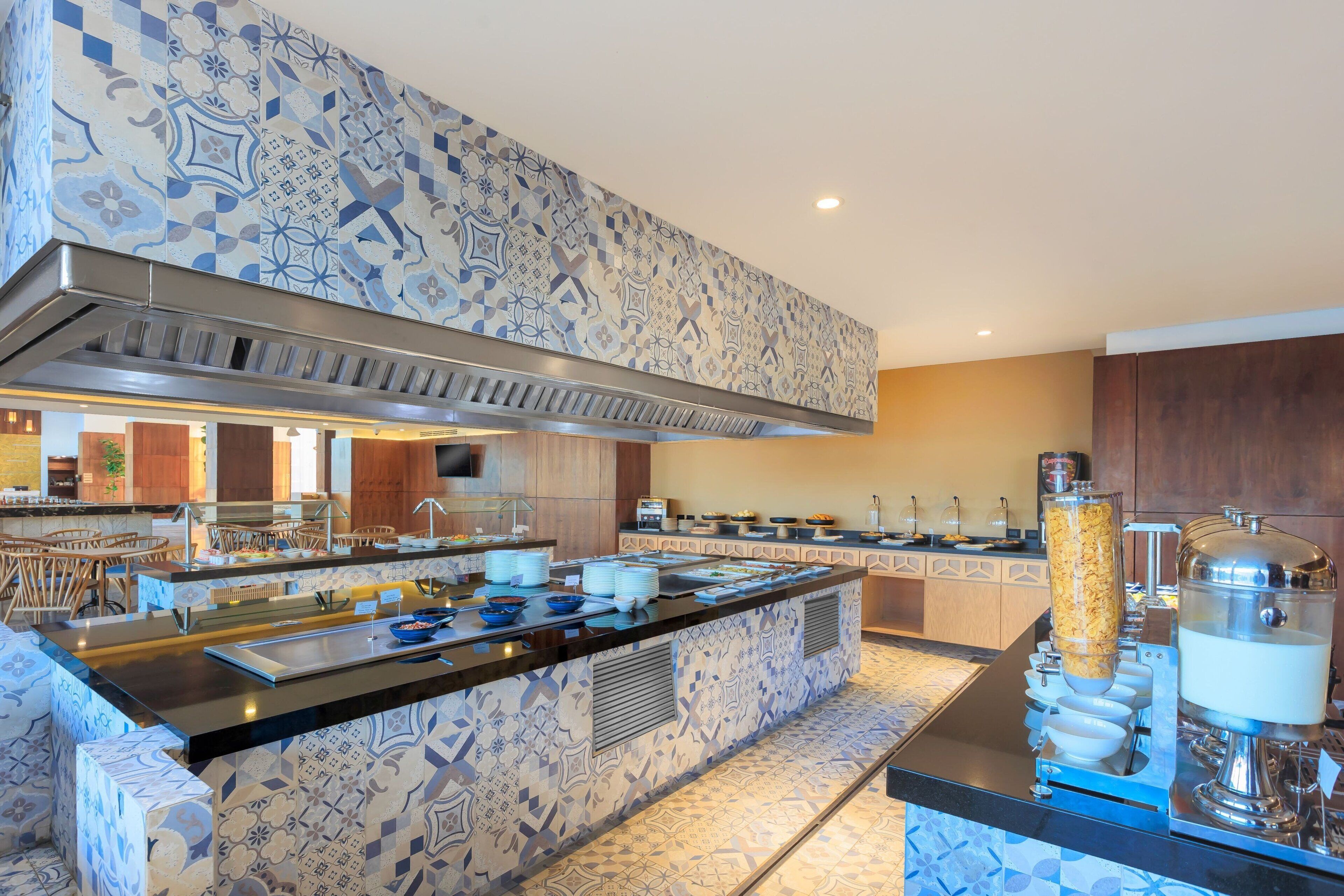 A modern kitchen with a patterned backsplash, a central island with a sink, and a buffet setup.