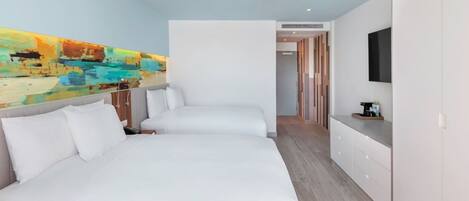 A modern hotel room with two beds, a large abstract painting on the wall, a flat-screen TV, and a wooden floor.
