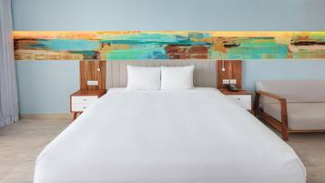 A modern hotel room with a large bed, wooden headboard, white bedding, a wooden nightstand with a phone, and a colorful abstract painting on the wall.