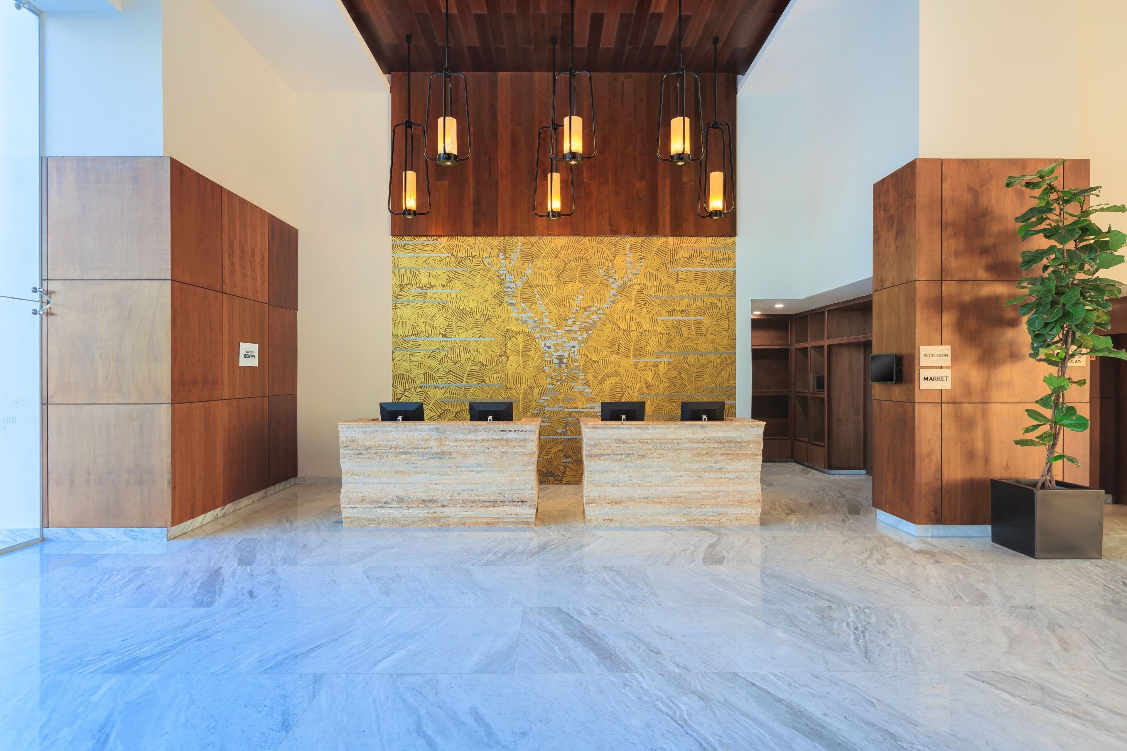 A reception area with a marble floor, wooden paneling, a large wall mural, and a reception desk with a plant.