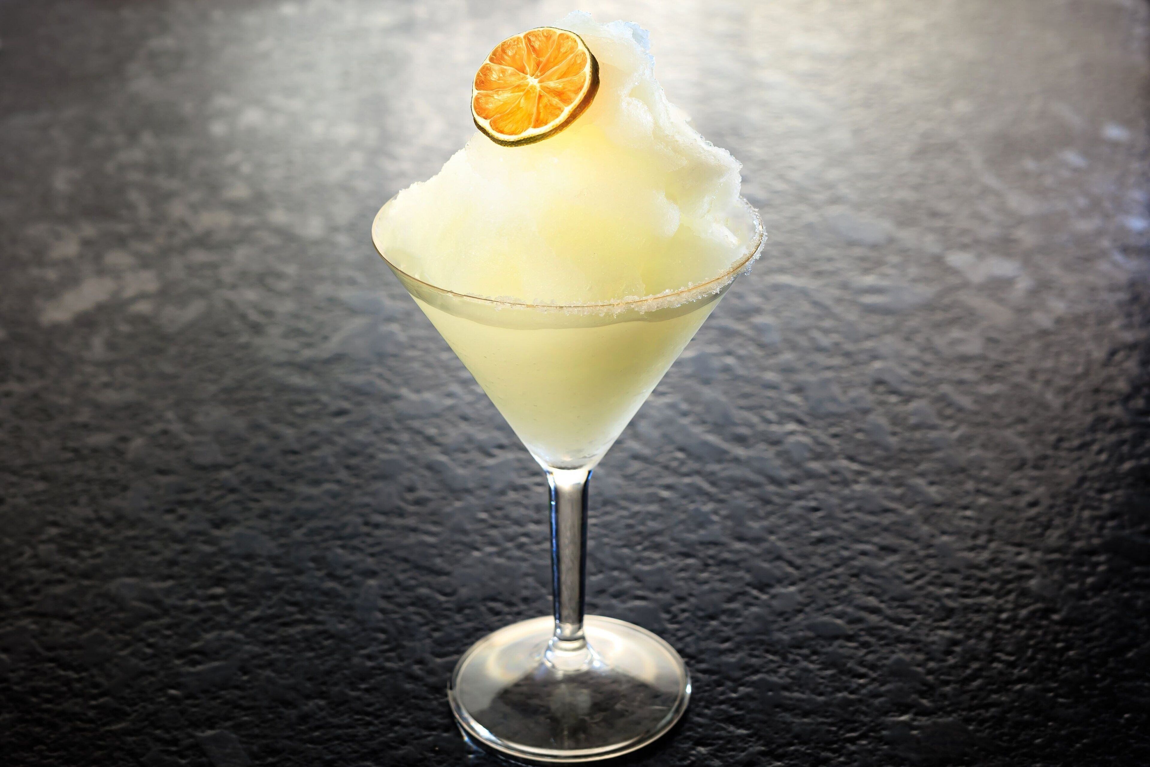 A cocktail in a martini glass with a slice of orange on top.